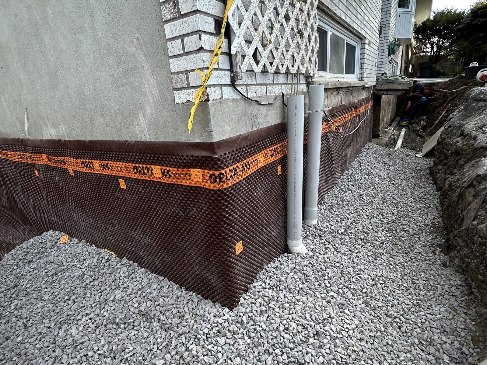Tranchée ouverte le long de la fondation d'un bungalow à Saint-Jean-sur-Richelieu avec un drain français neuf posé sur de la pierre nette